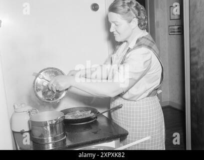 Current 1948 : femmes qui dirigent des doubles livesfemmes qui travaillent à double emploi. Elles participent à la vie professionnelle et sont aussi des ménagères. Mme Else Lund, ouvrière du textile, n'a pas le temps de s'ennuyer. Elle se lève à cinq heures et demie du matin et prépare le petit déjeuner pour son mari, qui doit aller travailler avant six heures. Ils ont deux fils, l'un âgé de quatre ans et l'autre âgé de huit ans et demi. Le plus jeune est en garderie quand la mère est à l'usine, de huit à seize ans. Le gamin de huit ans va à l'école à huit heures et demie. Mme Lund n'a pas de femme de ménage, il ne faut donc pas beaucoup d'imagination pour comprendre qu'elle n'a pas de femme de ménage. Banque D'Images