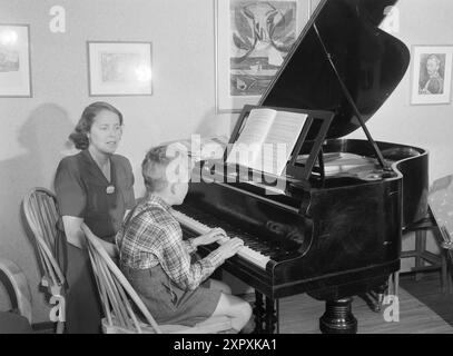 Current 1948 : femmes qui dirigent des doubles livesfemmes qui travaillent à double emploi. Elles participent à la vie professionnelle et sont aussi des ménagères. MRS Elsa Fagerhaug est une dame de standard, une grande entreprise de huit heures et demie à quatre heures et demie. Le petit fils de neuf ans est doué pour s'occuper de lui-même, mais avant de commencer l'école, il a dû être à la garderie. Mme Fagerhaug a une chambre et une cuisine, de sorte que le fils aîné, âgé de 16 ans, vit avec son père Nordland, où il va à l'école. Elle s'épanouit à la fois comme femme au foyer et avec son autre travail, même si elle n'a pas beaucoup de temps à perdre pour ce qu'elle aime Banque D'Images