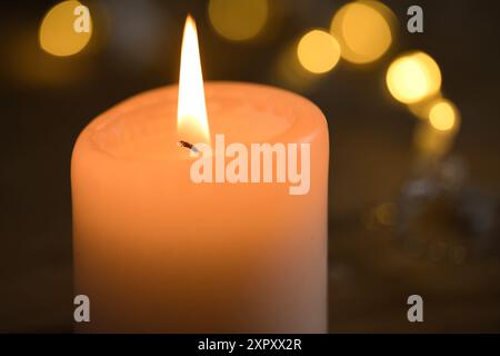 bougie allumée pour le 1er avent avec des lumières de noël en arrière-plan crée un beau bokeh chaud Banque D'Images