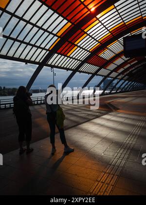 07.08.2024 , Amsterdam, pays-Bas, terminal de bus à la gare centrale au petit matin, lever du soleil et deux personnes féminines méconnaissables sur le pho Banque D'Images