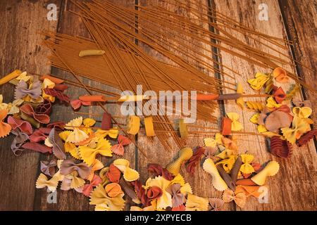 Diverses nouilles colorées avec des spaghettis à grains entiers sur un fond d'aspect bois Banque D'Images