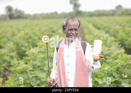 Agriculteur indien travaillant sur le champ agricole, pulvérisant de l'engrais sur le sol et les plantes. pauvre agriculteur, heureux agriculteur, vieil ouvrier agricole Banque D'Images