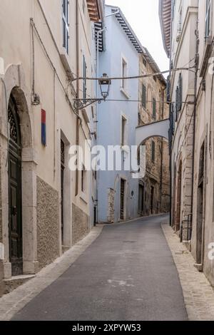 Paysage urbain avec une rue pittoresque et étroite en montée à la petite ville historique perchée au sommet d'une colline, tourné dans la lumière d'été à Amelia, Ombrie, Italie Banque D'Images