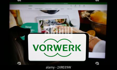Personne tenant un téléphone portable avec le logo de la société allemande d'appareils ménagers Vorwerk se Co. KG devant la page Web de l'entreprise. Concentrez-vous sur l'affichage du téléphone. Banque D'Images