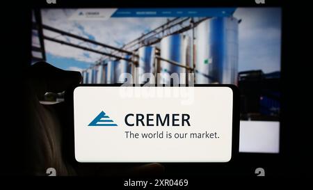Personne tenant un téléphone portable avec le logo de la société allemande Peter Cremer Holding GmbH Co. KG devant la page Web de l'entreprise. Concentrez-vous sur l'affichage du téléphone. Banque D'Images