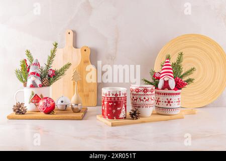 Deux tasses en céramique blanche élégantes avec un ornement de Noël rouge dans une composition festive de décorations pour la maison pour les vacances. Vue de face. Banque D'Images