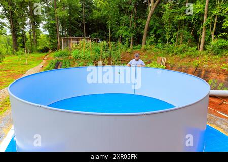 Le travailleur est actuellement en train d'installer le cadre métallique d'une piscine hors sol Banque D'Images