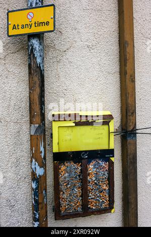 Un bac à cigarettes plein monté sur un mur dans le centre-ville de Brecon, Powys, pays de Galles Banque D'Images