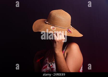 Belle femme debout portant une robe colorée avec un chapeau couvrant toute sa tête. Isolé sur fond fumé coloré. Banque D'Images