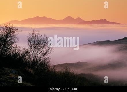 Îles du rhum et de l'Eigg dans les Hébrides intérieures vues depuis la péninsule d'Ardnamurchan à travers le brouillard marin entrant au coucher du soleil, Argyll, Écosse, mai 2002 Banque D'Images