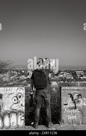 Un homme avec un sac à dos et un appareil photo photographiant le paysage urbain de Windhoek, Namibie. Banque D'Images