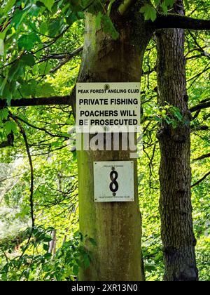 Signalisation sur un arbre indiquant une zone de pêche privée et avertissant contre le braconnage dans une forêt verdoyante. Banque D'Images