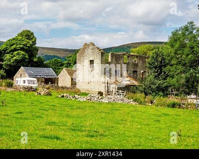 Bâtiment en pierre en ruine dans une campagne luxuriante avec des champs verdoyants et des nuages éparpillés. Banque D'Images