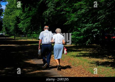 Couple âgé marchant sur une ruelle ombragée par une journée ensoleillée. Prise en août 2024. Été Banque D'Images