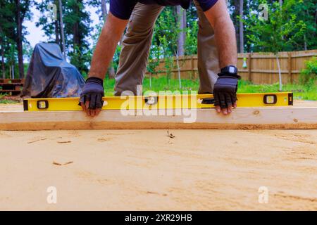 Lors de la préparation de la plate-forme pour l'installation de la piscine dans la cour arrière, nivellement du sable Banque D'Images