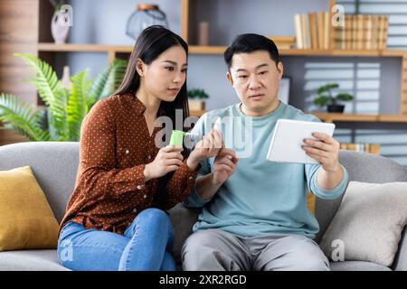 Famille asiatique ayant consultation en ligne avec le médecin par appel vidéo sur tablette. Deux personnes discutant de problèmes de santé, montrant des médicaments et suivant les conseils du médecin. Banque D'Images