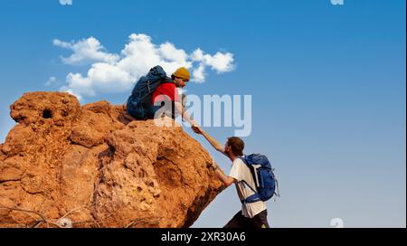 Deux randonneurs grimpant jusqu'à la falaise de montagne et l'un d'entre eux donnant un coup de main - aventure et concept de voyage. Banque D'Images
