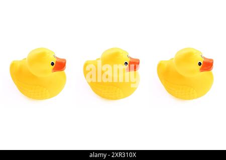 Trois canards en caoutchouc jaunes dans une ligne sur fond blanc Banque D'Images