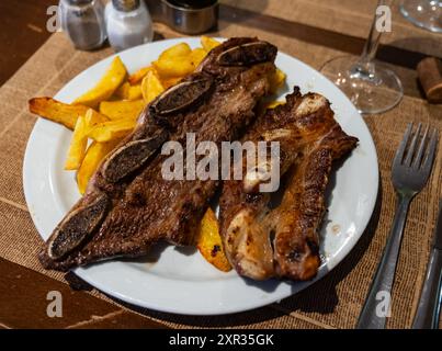 Sur des côtes de bœuf grillées blanches garnies de pommes de terre frites Banque D'Images