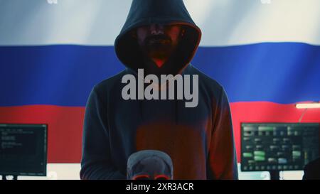 Cyber-criminel russe faisant des menaces de mort nuisibles avec un crâne, image conceptuelle du cyberterrorisme et de la cybercriminalité. Une personne avec un capot sombre incarnant la terreur et la panique parmi la population. Caméra B. Banque D'Images