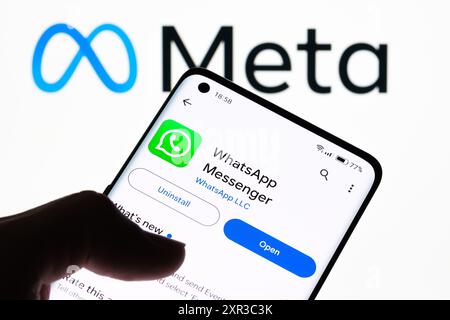 Gros plan d'un écran de smartphone affichant l'application WhatsApp Messenger avec le logo Meta en arrière-plan, démontrant la relation entre WhatsApp an Banque D'Images