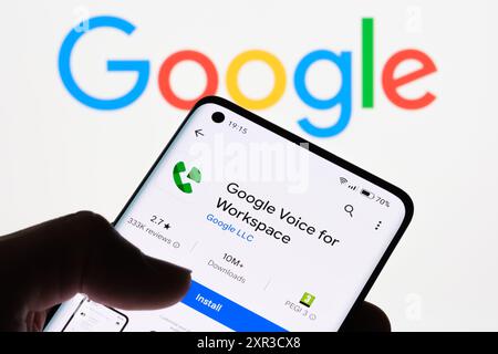 Gros plan de l'écran d'un smartphone affichant l'application Google Voice pour Workspace avec le logo Google en arrière-plan, montrant le lien entre Google Voice fo Banque D'Images
