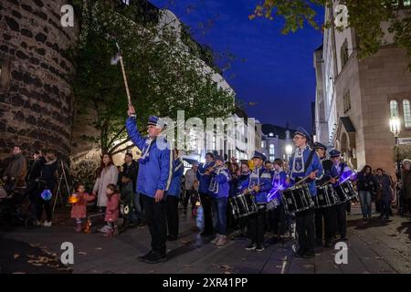 Cette image animée capture un groupe de musique se produisant la nuit à Bonn, en Allemagne. Le groupe, vêtu d'uniformes traditionnels, parade dans les rues, Banque D'Images