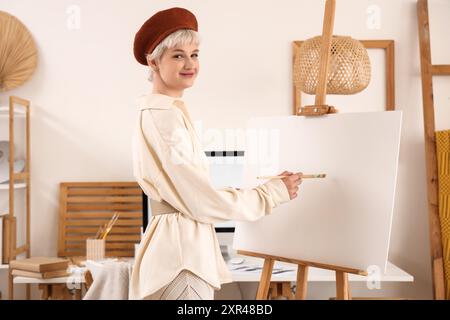 Jeune femme en béret dessinant sur toile dans un bureau élégant Banque D'Images