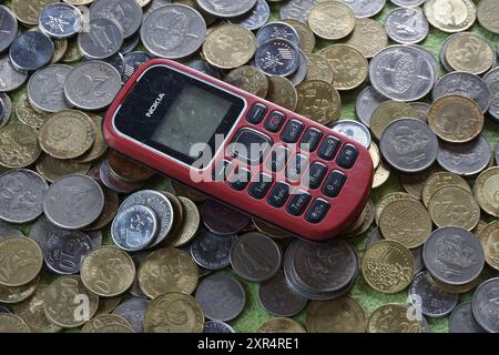 Terengganu, Malaisie - 24 août 2024 : gros plan de téléphones nokia rouges à clavier sur des pièces de monnaie malaisiennes dispersées Banque D'Images