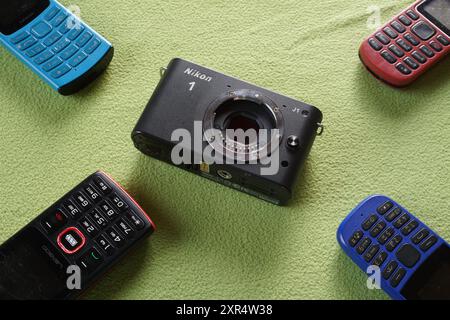 Terengganu, Malaisie - 24 août 2024 : gros plan de nikon 1 j1 appareil photo sans miroir et divers téléphones à clavier sur fond vert Banque D'Images