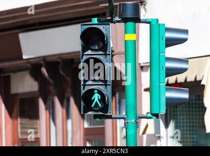 Feu de circulation affichant un panneau vert indiquant qu'il est sûr pour les piétons de traverser la rue. Le signal vert de passage pour piétons est allumé, indicat Banque D'Images