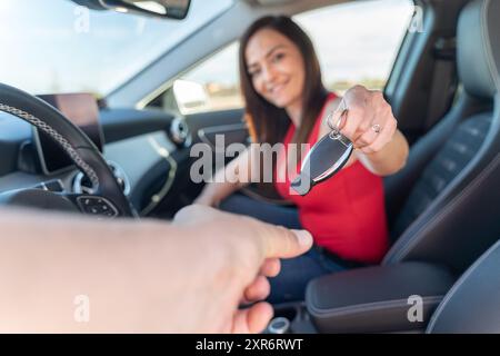 Une vendeuse remet la clé de la voiture au client - employé de Rent a car à l'intérieur du véhicule Banque D'Images