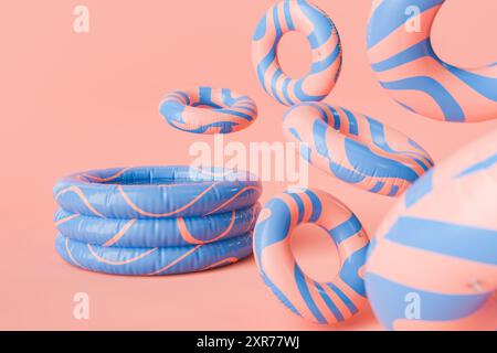 Rendu 3D d'une piscine gonflable avec des anneaux de natation gonflables rayés bleus et rouges flottant dans l'air avec un fond de corail ludique. Plaisir estival et Banque D'Images