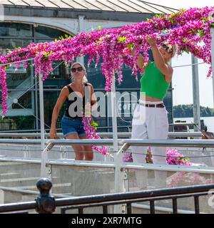 Deux belles femmes en lunettes de soleil, décorer le coin salon extérieur de leur café avec des fleurs. Cardiff Bay, Cardiff. ROYAUME-UNI. Banque D'Images
