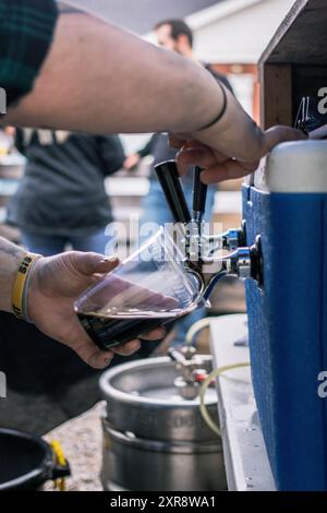 Verser une bière brune dans un jardin en plein air Banque D'Images