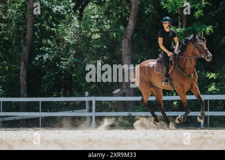 Jeune femme à cheval dans une arène forestière par une journée ensoleillée Banque D'Images