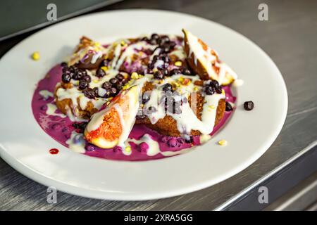 Dessert sucré avec figue, myrtille et sauce crémeuse sur assiette, gros plan. Banque D'Images