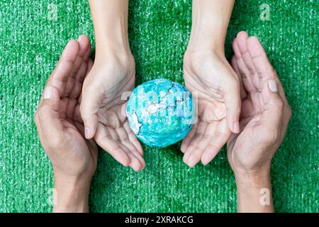 Environnement jour de la Terre dans les mains tenant la terre verte sur fond vert Bokeh, sauver l'environnement, et écologiquement durable. Sauvez la Terre. CON Banque D'Images