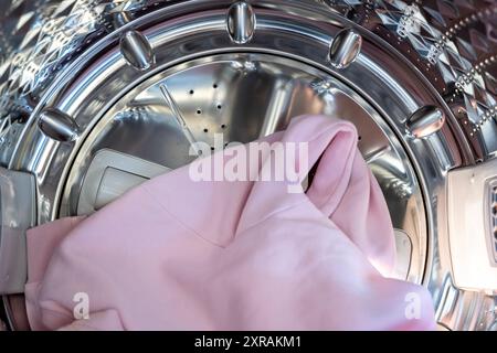 Vue rapprochée sur le sèche-linge avec chemises lavées et séchées et porte ouverte. Tambour métallique de la machine à laver pour laver les vêtements dans le ménage. Banque D'Images