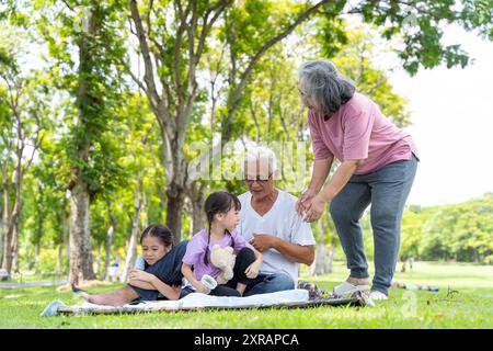 Grands-parents s'amusant avec leurs petits-enfants dans le parc de la ville. Adorable petite-fille et grands-parents jouant dehors au parc. Banque D'Images