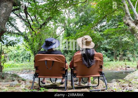 Couple assis sur une chaise dans un camping confortable ou maison de campagne vie informelle dans la nature. Escapades du week-end millénaire aux séjours d'une nuit Banque D'Images