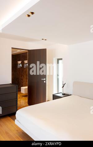 Détail de la chambre dans la villa moderne. Porte ouverte sur la salle de bains avec sol en marbre dans la suite. Personne à l'intérieur Banque D'Images