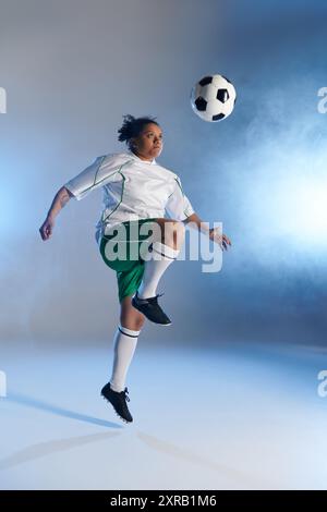 Une joueuse de football féminine saute haut, les yeux fixés sur le ballon, sur le point de faire un jeu puissant. Banque D'Images