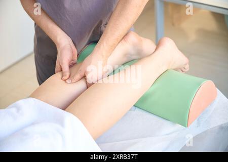 Masseur effectuant le massage des jambes sur la femme adulte Banque D'Images