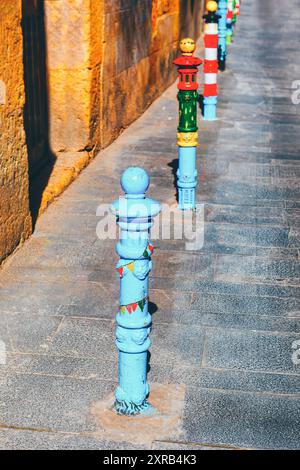 Une rangée vibrante de bâtons colorés se dresse le long d'un trottoir, ajoutant une touche joyeuse au paysage urbain Banque D'Images