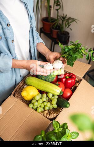 Personne déballer la commande en ligne de fruits et légumes cultivés à la ferme, tenant l'ail blanc dans ses mains. Banque D'Images