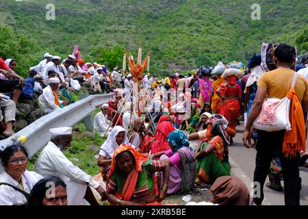 Pune, Maharashtra, Inde, 2 juillet 2024, les pèlerins ou warkari portant des drapeaux safran participent à une procession religieuse pendant le Pandarpur yatra sur la route D. Banque D'Images