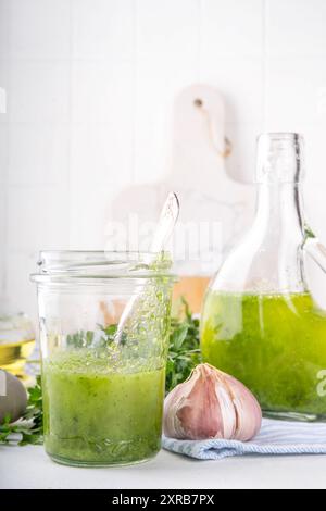 Vinaigrette aromatique culinaire aux herbes vertes. Basilic frais infusé, huile d'olive à l'ail persil pour la cuisson du dîner, avec salade verte sur fond de cuisine Banque D'Images