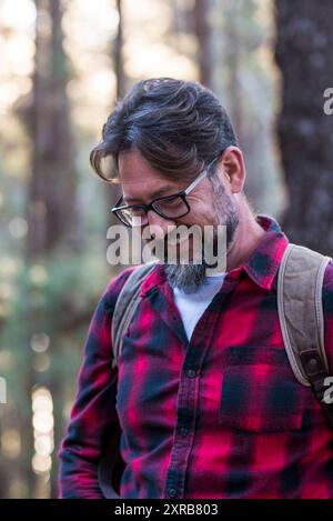 Homme en randonnée et en appréciant dans une forêt de bois. Vue latérale d'un homme portant un sac marchant dans une forêt. Heureux adulte jeune caucasien portrait masculin appréciant la nature saine style de vie activité de loisirs en plein air Banque D'Images