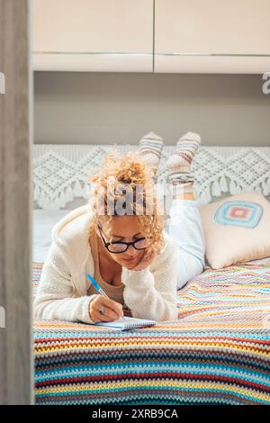 Une femme indépendante planifiant un voyage sur route à destination suivante, posée sur le lit dans sa chambre de camionnette de camping. Concept de vacances alternatives et de vie hors-réseau de van. Loisirs modernes Banque D'Images